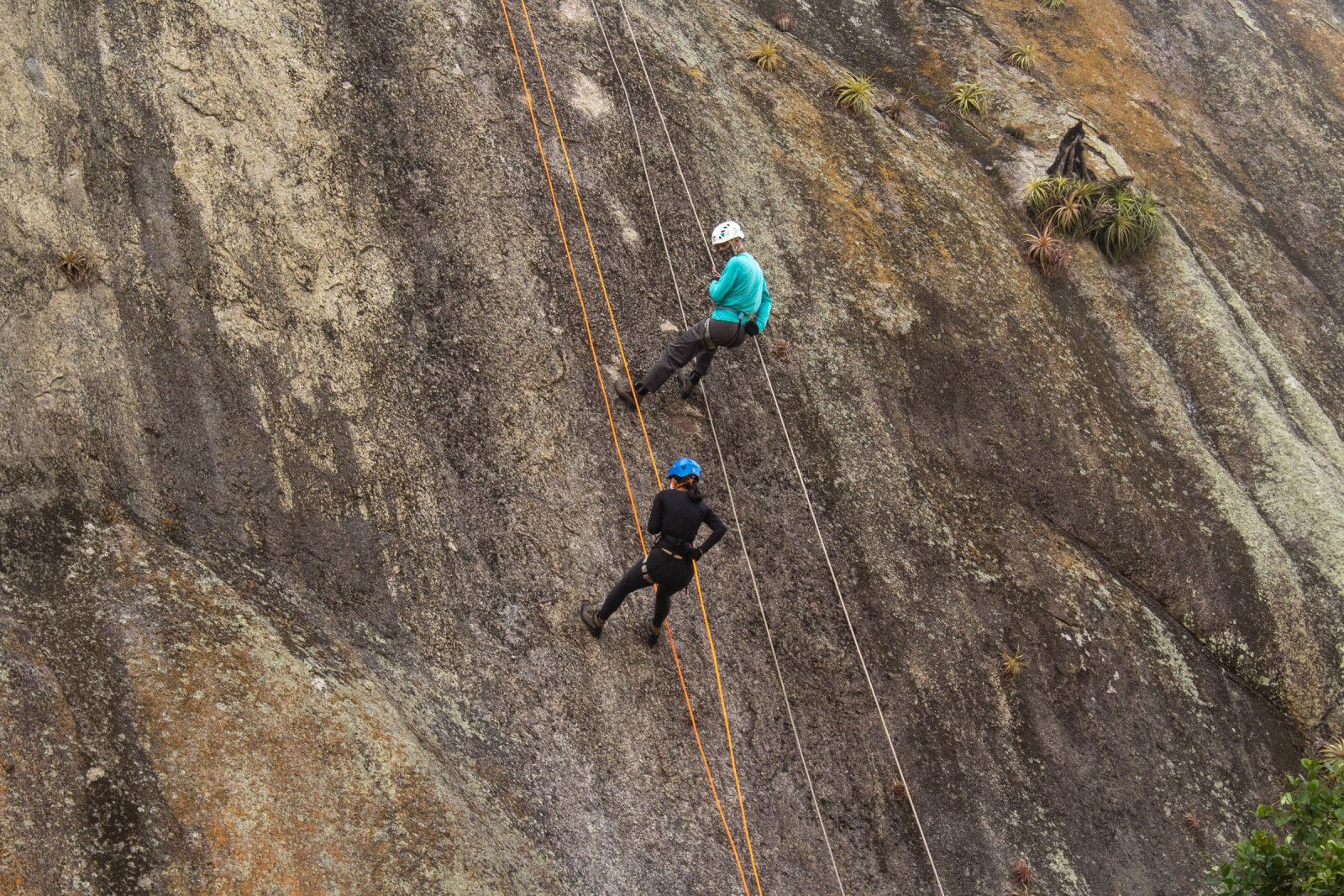 Two climbers abseiling a steep granite slab