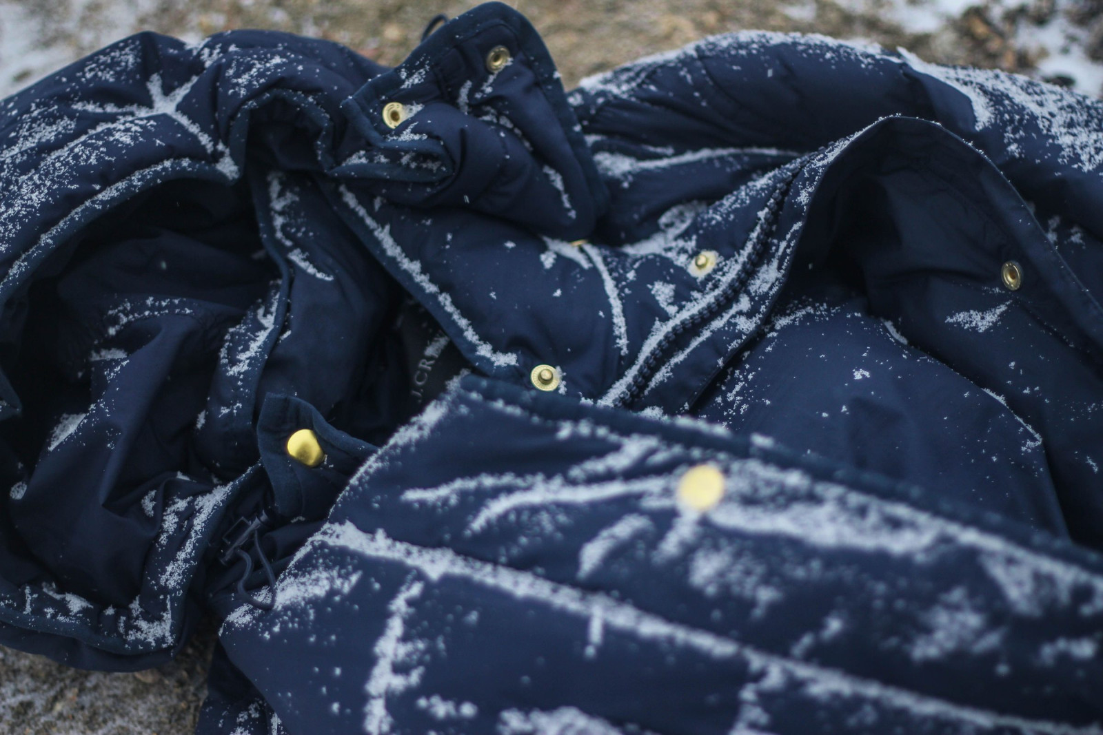 Navy down jacket dusted with snow, close up
