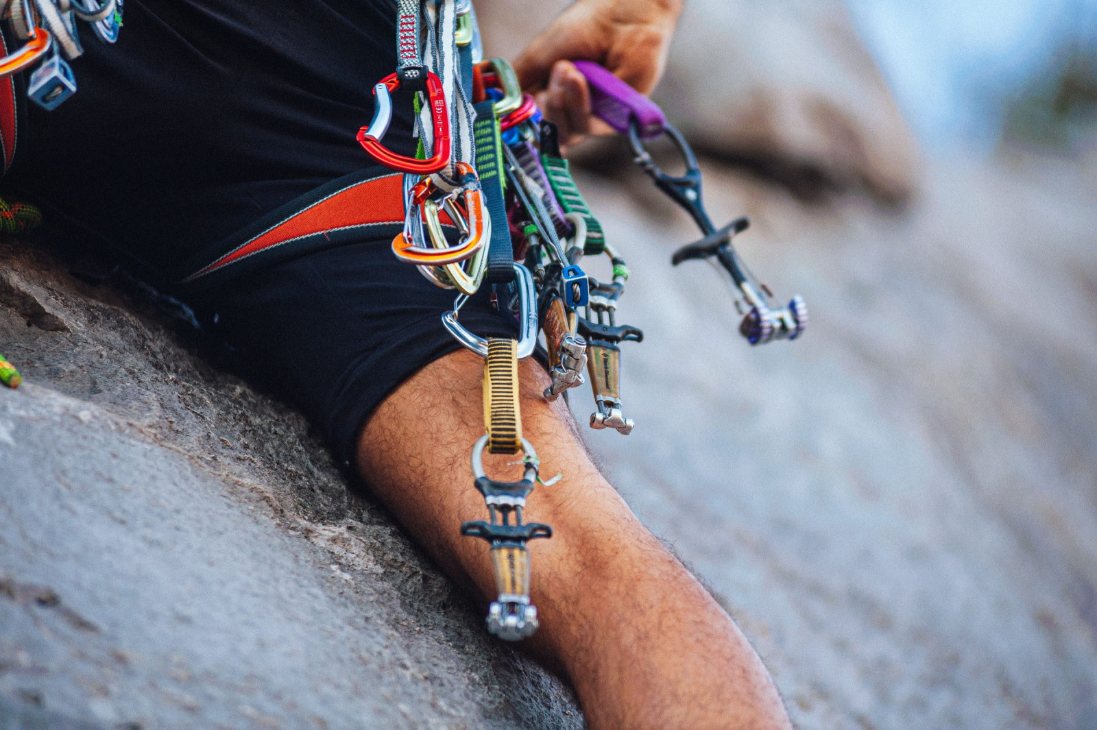 Cams and carabiners racked on a climber's harness against granite